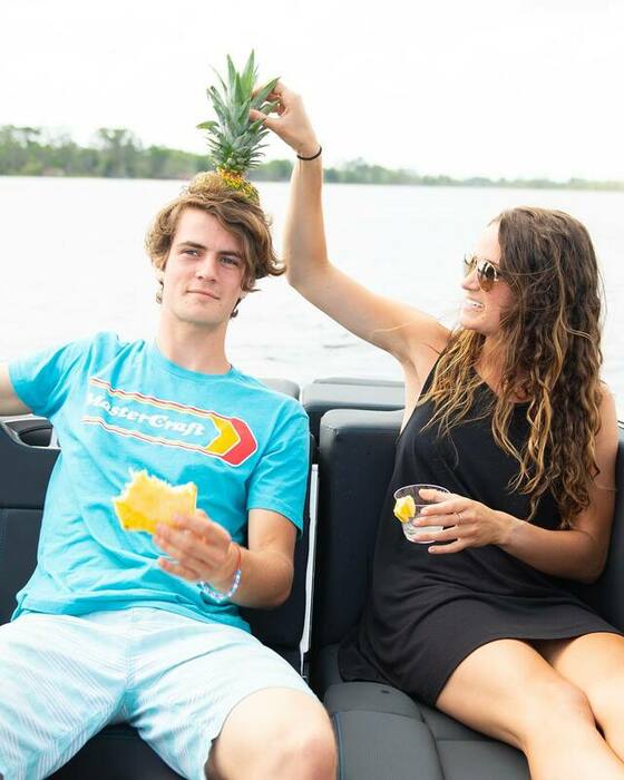 Man and Woman sitting on a boat while eating pineapple
