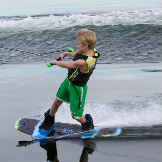 Young boy wake boarding on a Connelly board and wearing a Connelly vest